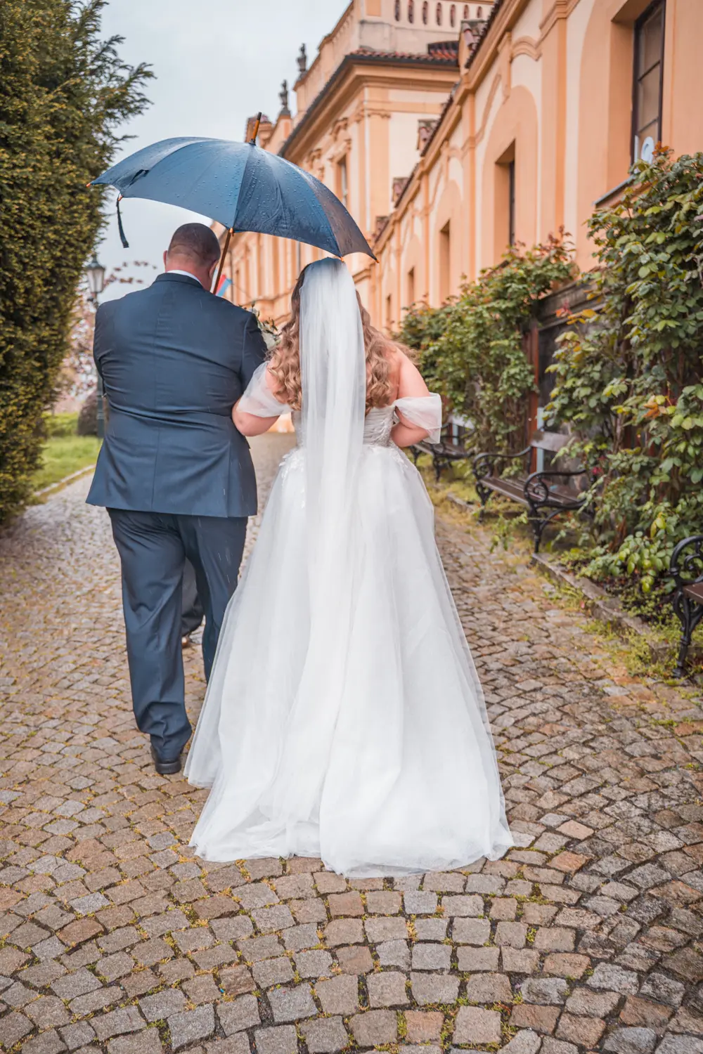 Nevěsta a ženich s deštníkem u zámku